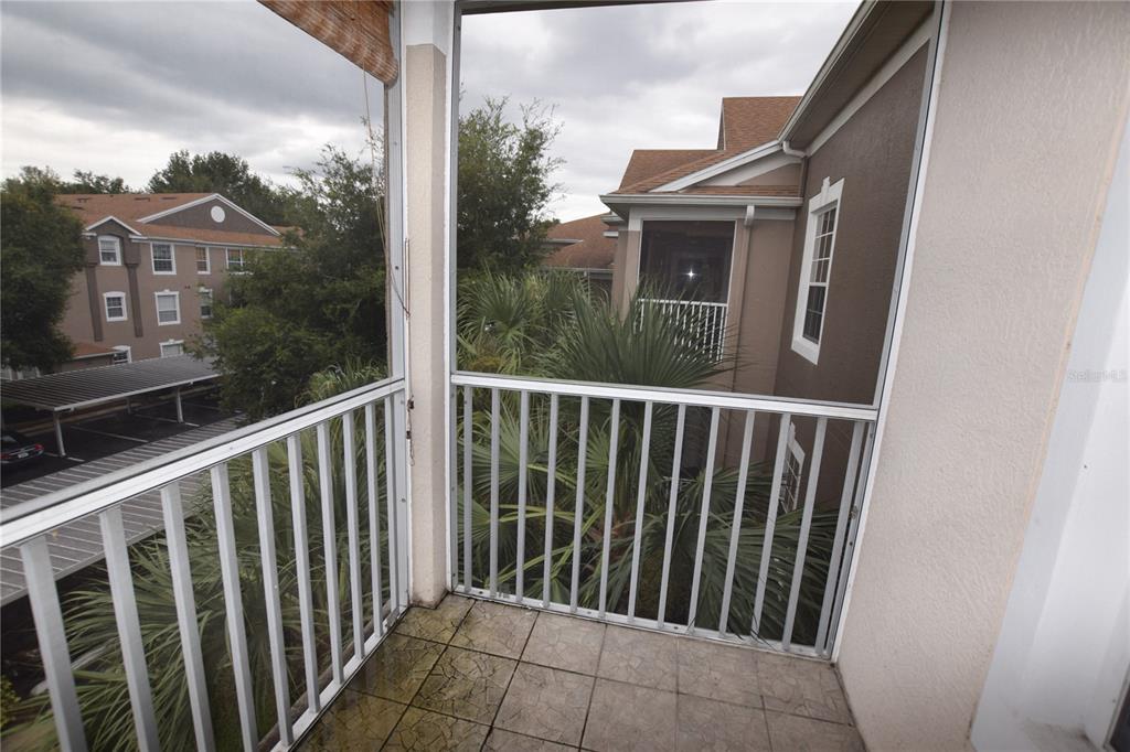 A screened-in balcony with tiled flooring overlooks a parking area and surrounding apartment buildings — 7109 YACHT BASIN AVENUE UNIT 435, ORLANDO, FL