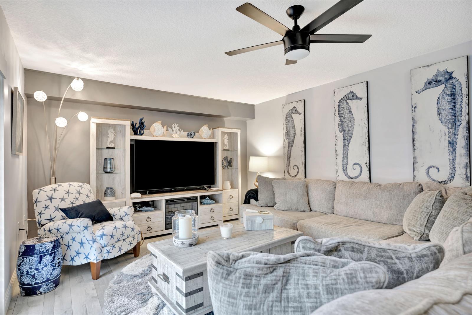 A coastal-themed living room features a sectional sofa, patterned armchair, and a large media console — 1209 12th Court, Jupiter FL 33477, JUPITER, FL