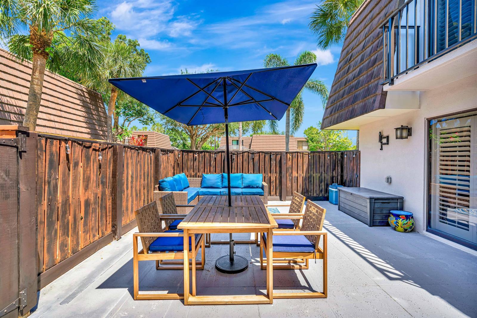 A patio features a wooden dining set with blue cushions under a blue umbrella — 1209 12th Court, Jupiter FL 33477, JUPITER, FL