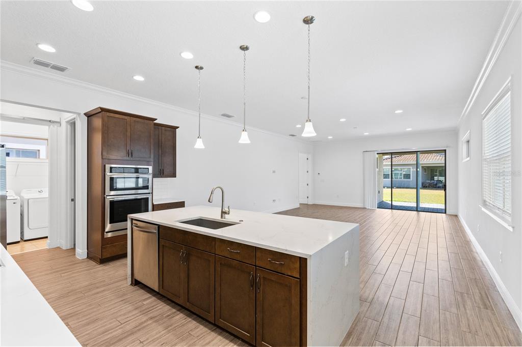 A kitchen with a large island, dark wood cabinets, and stainless steel appliances overlooks a living area — 13300 BROMBOROUGH DRIVE, ORLANDO, FL