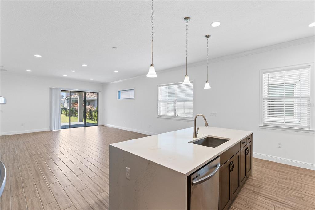 A kitchen island with a sink and dark cabinets overlooks an open-concept living area — 13300 BROMBOROUGH DRIVE, ORLANDO, FL