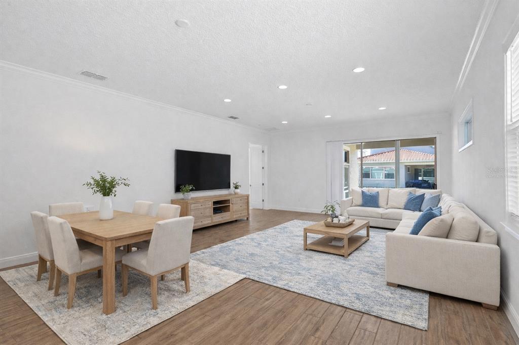 A bright, open-concept living and dining area features light wood floors and neutral furniture — 13300 BROMBOROUGH DRIVE, ORLANDO, FL