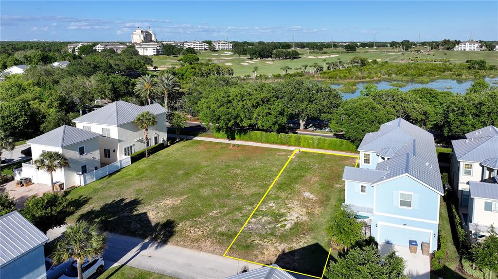 An aerial view shows a vacant residential lot situated between two houses near a golf course — 1426 REUNION BOULEVARD, REUNION, FL