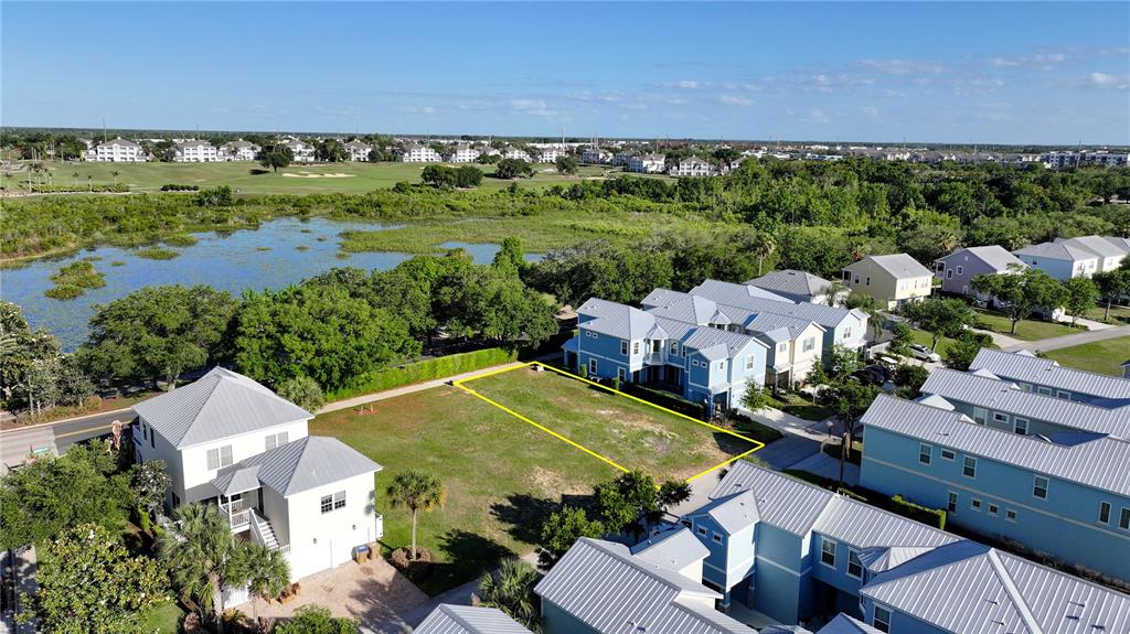 An aerial view shows a vacant rectangular lot outlined in yellow between residential buildings — 1426 REUNION BOULEVARD, REUNION, FL