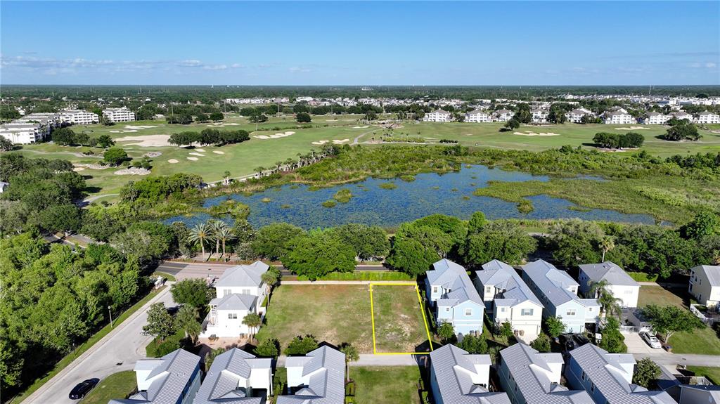 An aerial view shows a vacant residential lot outlined in yellow between two rows of houses — 1426 REUNION BOULEVARD, REUNION, FL