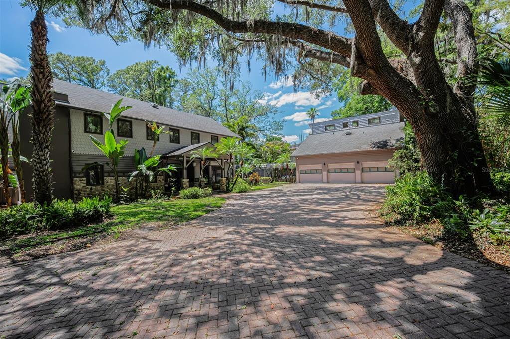 A two-story house with a detached three-car garage and a large brick-paved driveway — 8602 BONNIE COVE LANE, ODESSA, FL