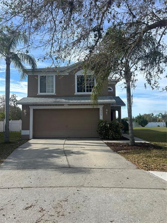 A two-story house with a tan stucco exterior, a two-car garage, and palm trees — 1906 SHERBOURNE STREET, WINTER GARDEN, FL