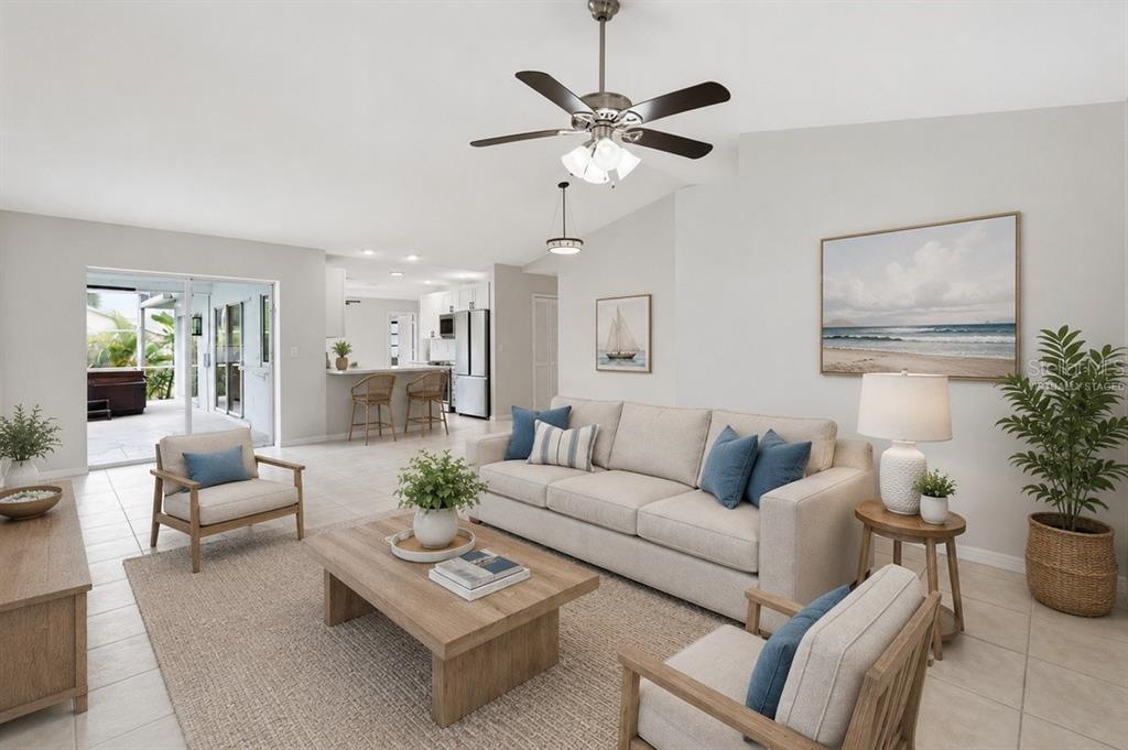 This virtually staged living room features a beige sofa, two armchairs, and a ceiling fan — 524 SE 8TH PLACE, CAPE CORAL, FL