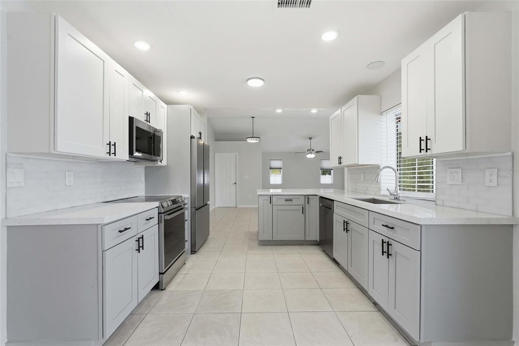 A kitchen features white upper cabinets, gray lower cabinets, stainless steel appliances, and tile flooring — 524 SE 8TH PLACE, CAPE CORAL, FL