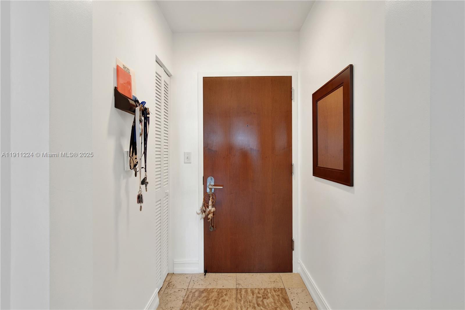 An entryway features a wooden door, a louvered closet door, and a wall-mounted mirror — 31 SE 5th St # 2910, Miami FL 33131, MIAMI, FL