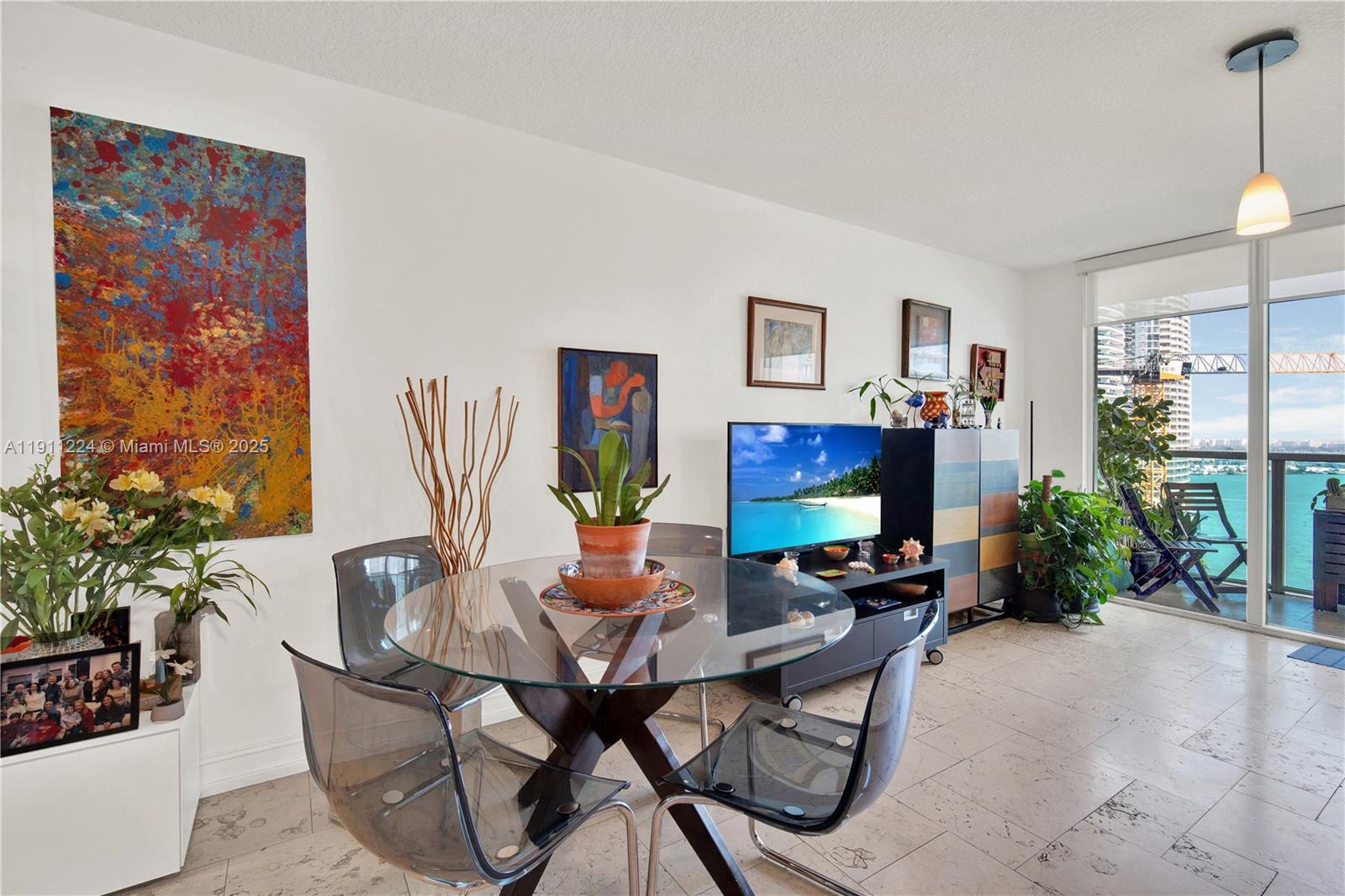 A dining area with a glass table and transparent chairs sits before a balcony view — 31 SE 5th St # 2910, Miami FL 33131, MIAMI, FL
