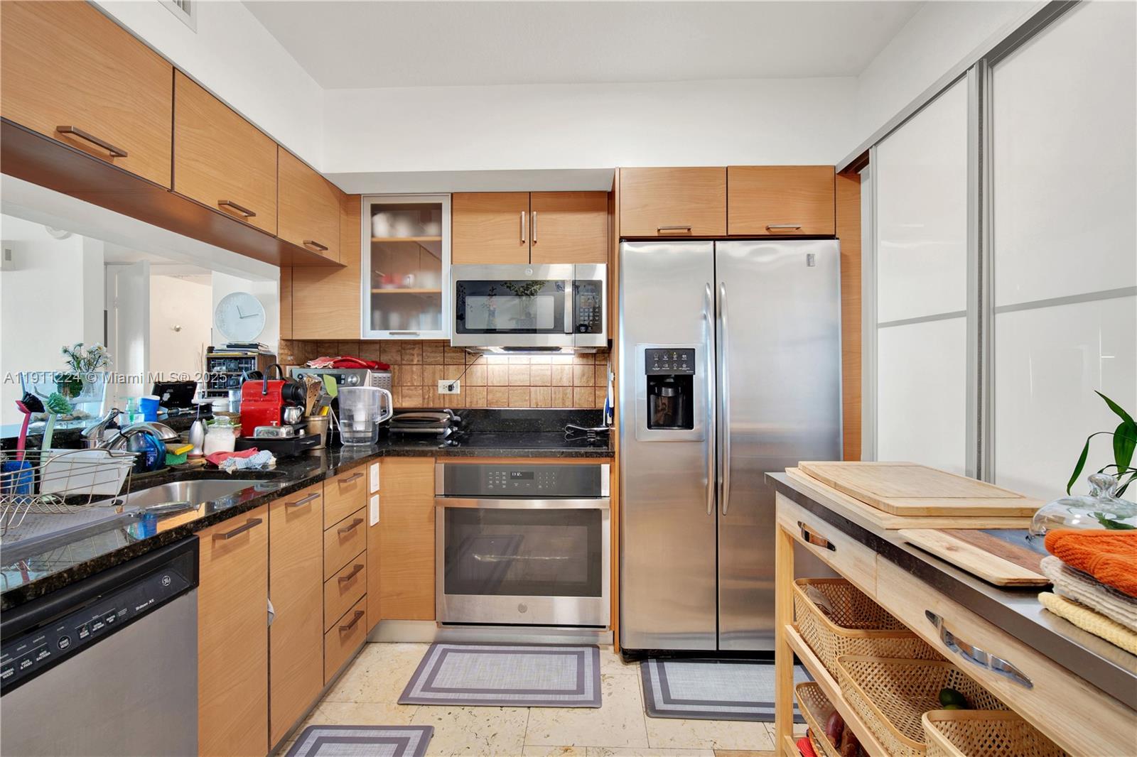 A kitchen features light wood cabinets, stainless steel appliances, and dark granite countertops — 31 SE 5th St # 2910, Miami FL 33131, MIAMI, FL