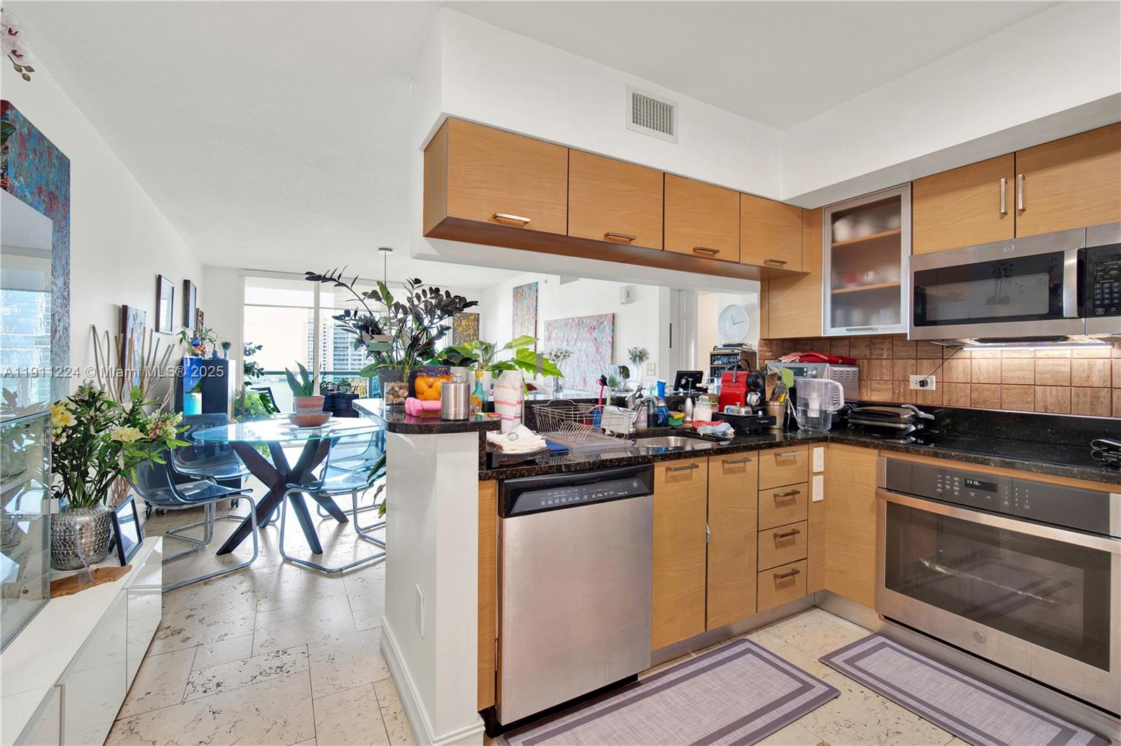 A kitchen with light wood cabinets, stainless steel appliances, and a dining area nearby — 31 SE 5th St # 2910, Miami FL 33131, MIAMI, FL
