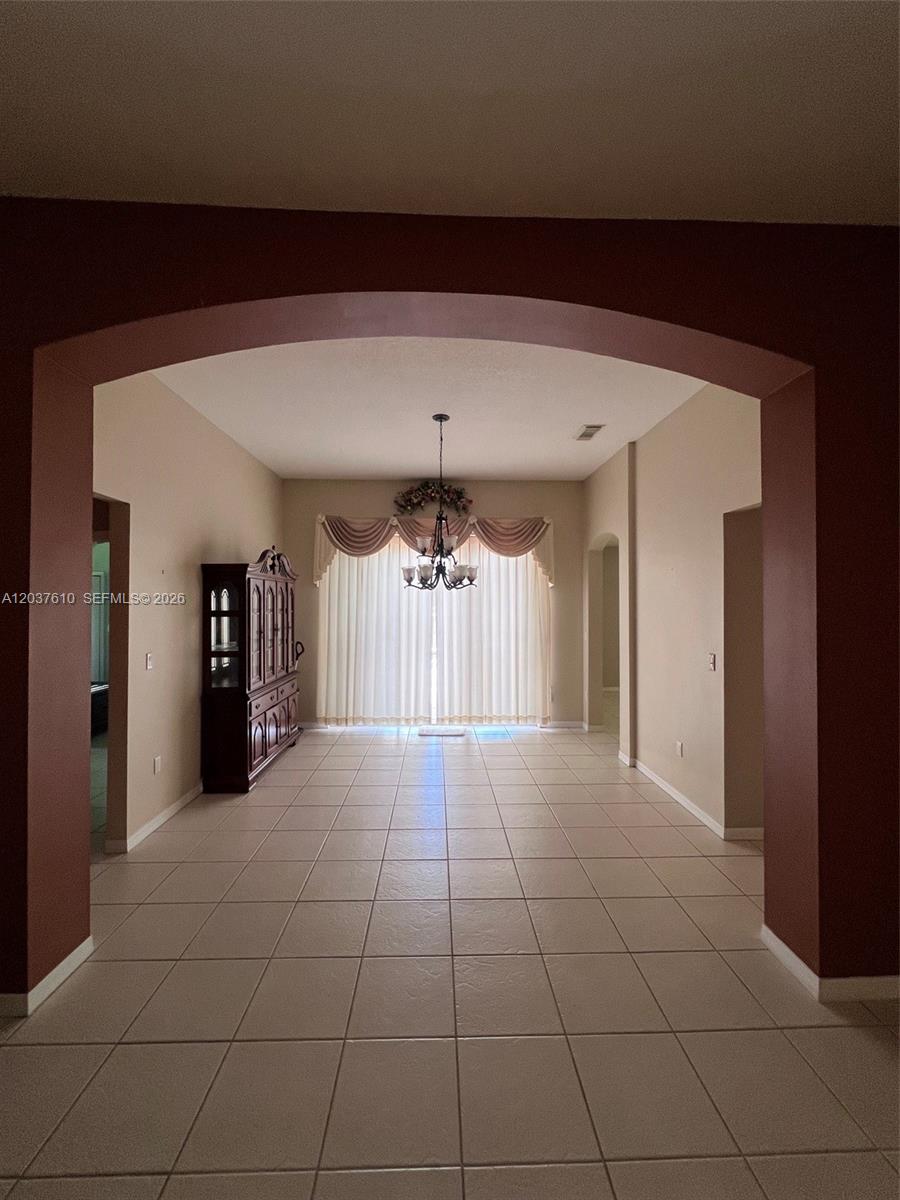 A dining room with tile floors, a chandelier, and a large dark wood china cabinet — 10155 SW 159th Ct, Miami FL 33196, MIAMI, FL