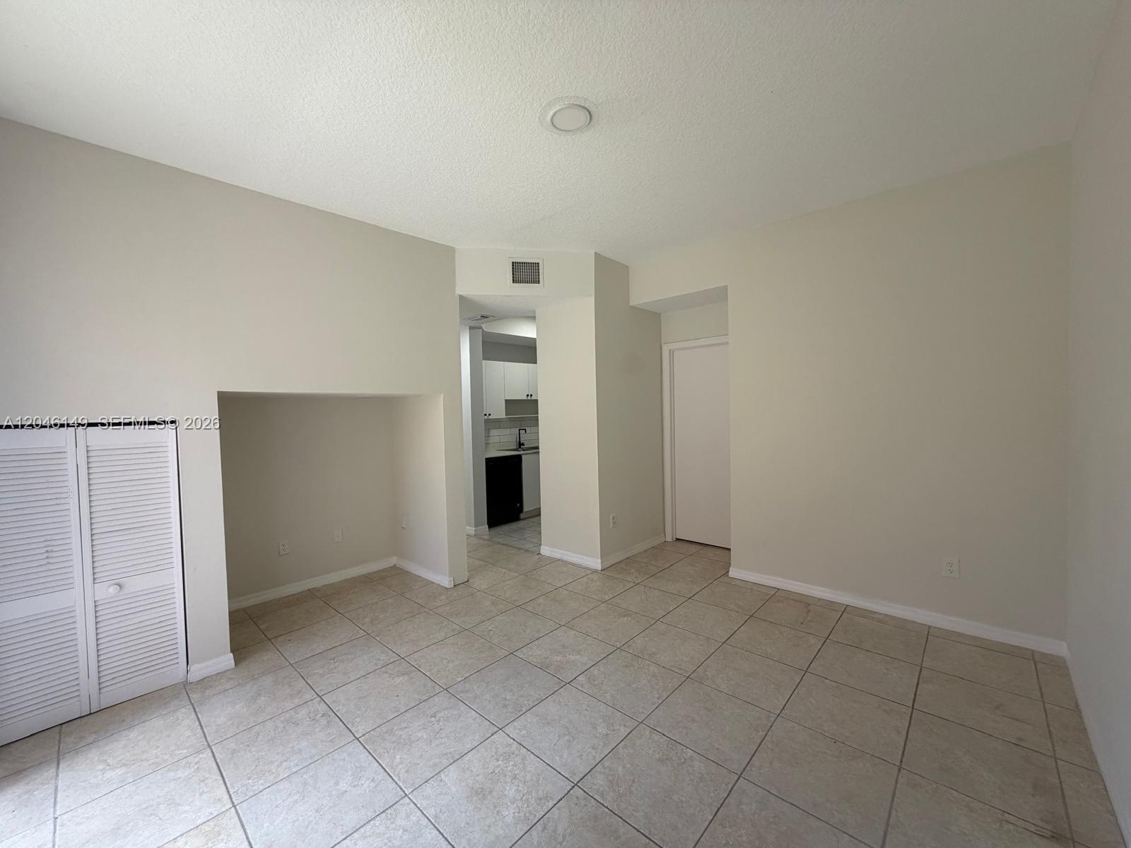 An empty room with beige tile flooring, a recessed nook, and a doorway to a kitchen — 2201 Clipper Pl # 5405, Dania Beach FL 33312, DANIA BEACH, FL