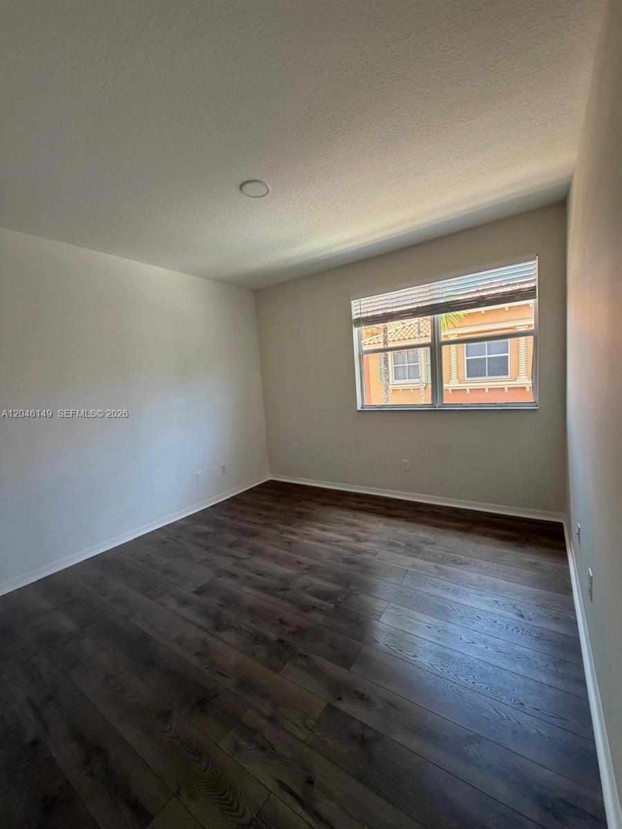 An empty room features dark wood-look flooring, light-colored walls, and a single window — 2201 Clipper Pl # 5405, Dania Beach FL 33312, DANIA BEACH, FL