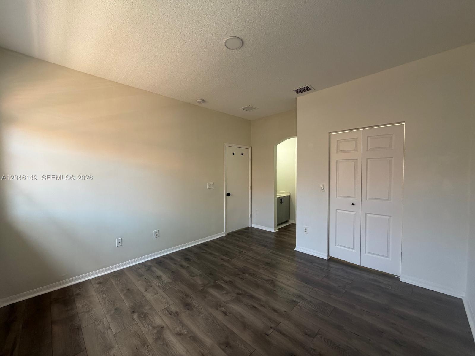 An empty room features wood-look flooring, white walls, a closet, and an arched doorway — 2201 Clipper Pl # 5405, Dania Beach FL 33312, DANIA BEACH, FL