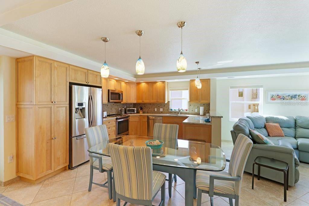 A kitchen with light wood cabinets, stainless steel appliances, and a glass dining table — 6154 MIDNIGHT PASS ROAD UNIT 201, SARASOTA, FL