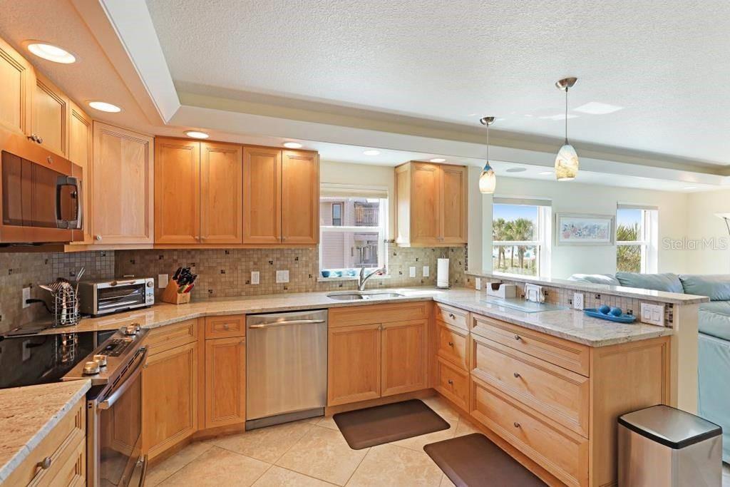 A kitchen with light wood cabinets, granite countertops, stainless steel appliances, and tile flooring — 6154 MIDNIGHT PASS ROAD UNIT 201, SARASOTA, FL
