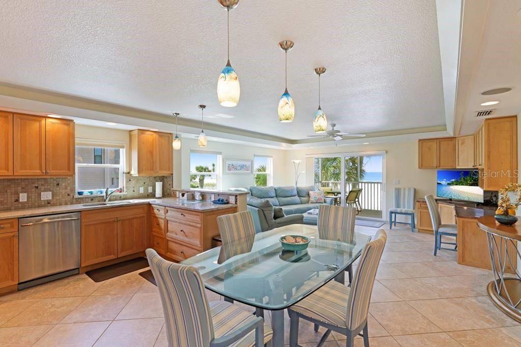 An open-concept kitchen and dining area with light wood cabinets, tile floors, and ocean views — 6154 MIDNIGHT PASS ROAD UNIT 201, SARASOTA, FL