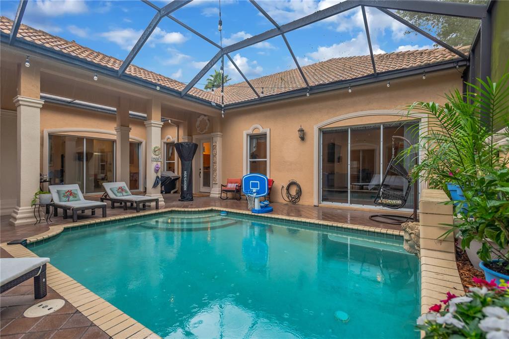 A screened-in patio features a swimming pool, lounge chairs, and a basketball hoop — 1034 W SKYVIEW LANDINGS DRIVE, HERNANDO, FL