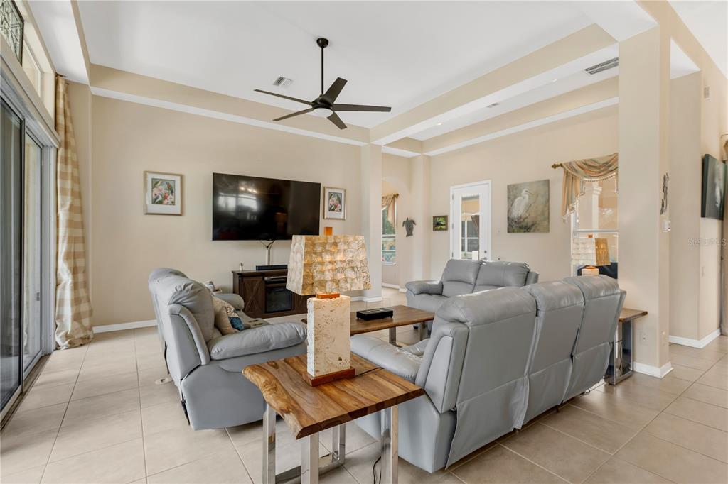 A living room features light tile floors, gray leather sofas, and a high tray ceiling — 1034 W SKYVIEW LANDINGS DRIVE, HERNANDO, FL
