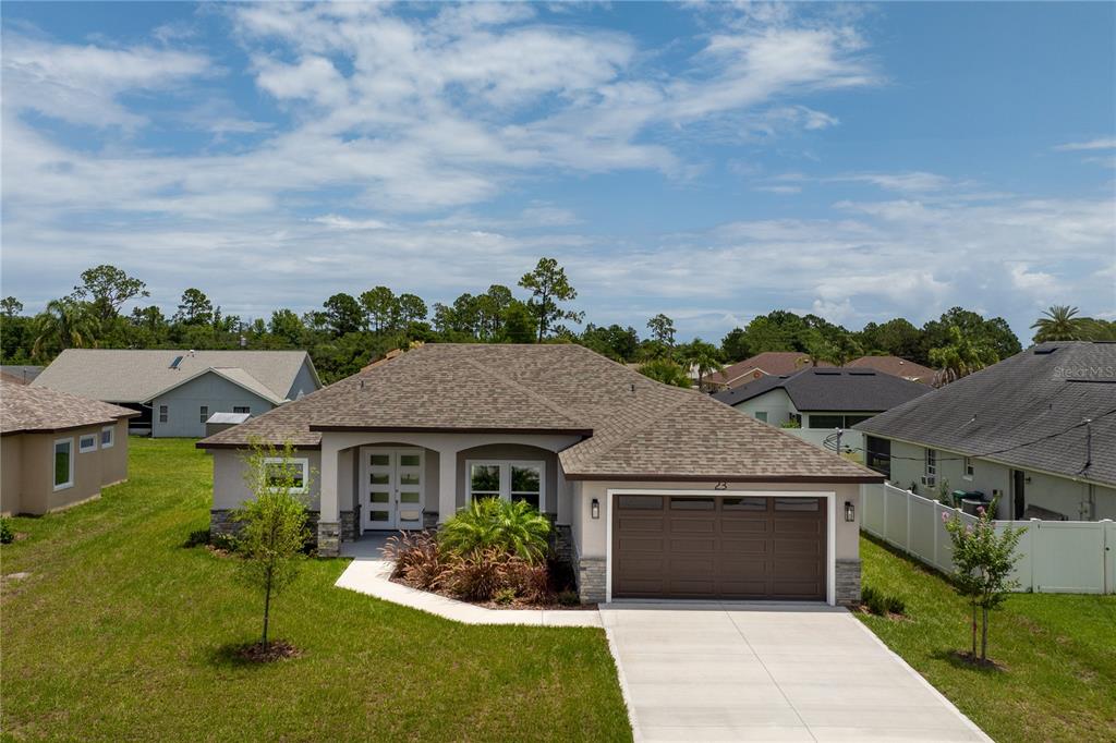 A single-story suburban house with a brown shingle roof, tan siding, and a two-car garage — 23 FRANCIS LANE, PALM COAST, FL