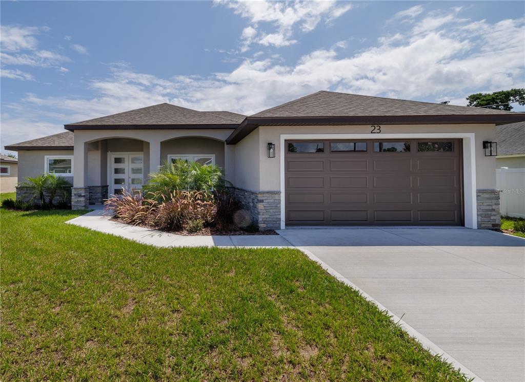 A single-story house with a brown garage door, stone accents, and a concrete driveway — 23 FRANCIS LANE, PALM COAST, FL