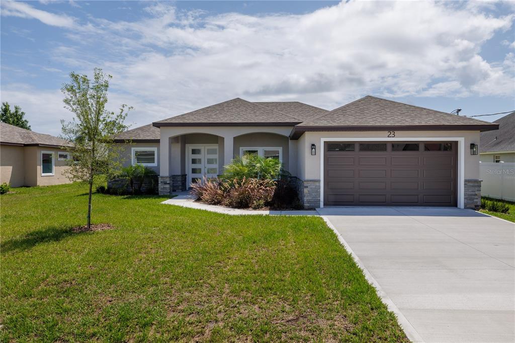 A single-story house with a brown garage door, stone accents, and a front lawn — 23 FRANCIS LANE, PALM COAST, FL