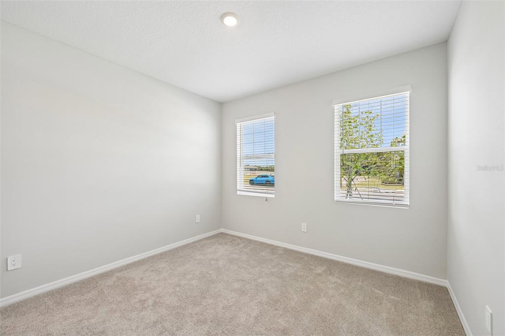 An empty bedroom with light gray walls, beige carpet, and two windows with white blinds — 9927 HIDDEN HAMMOCK LOOP, PARRISH, FL
