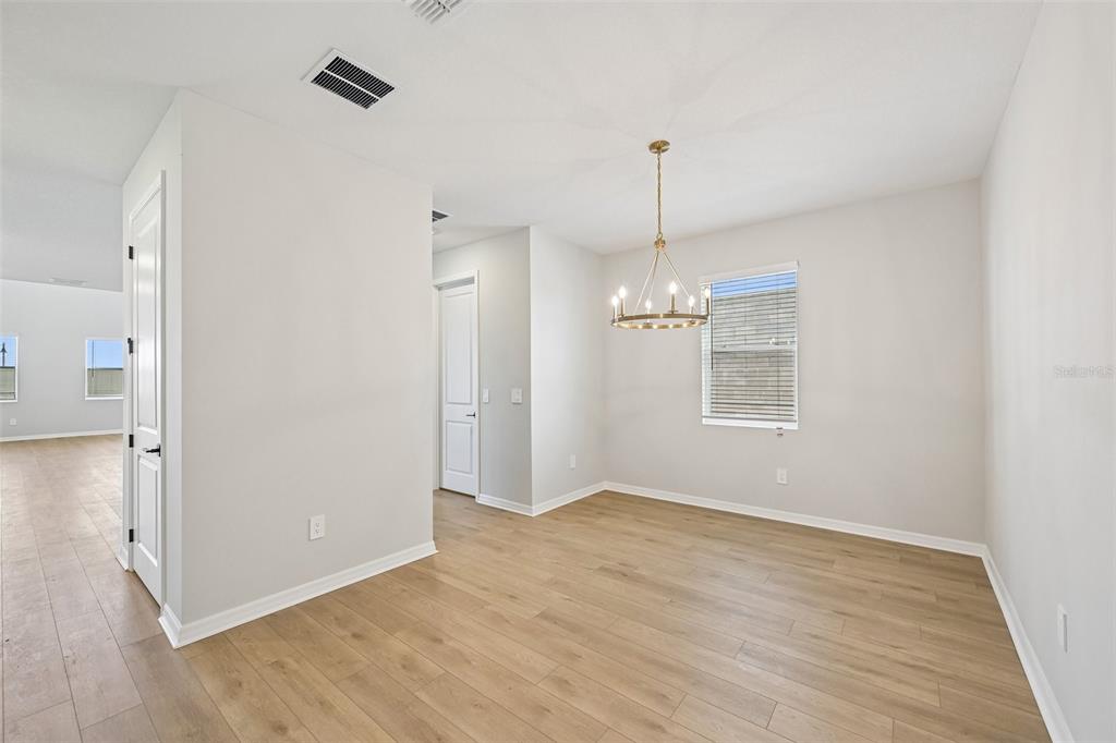 A dining room with light wood flooring, white walls, and a gold chandelier — 9927 HIDDEN HAMMOCK LOOP, PARRISH, FL