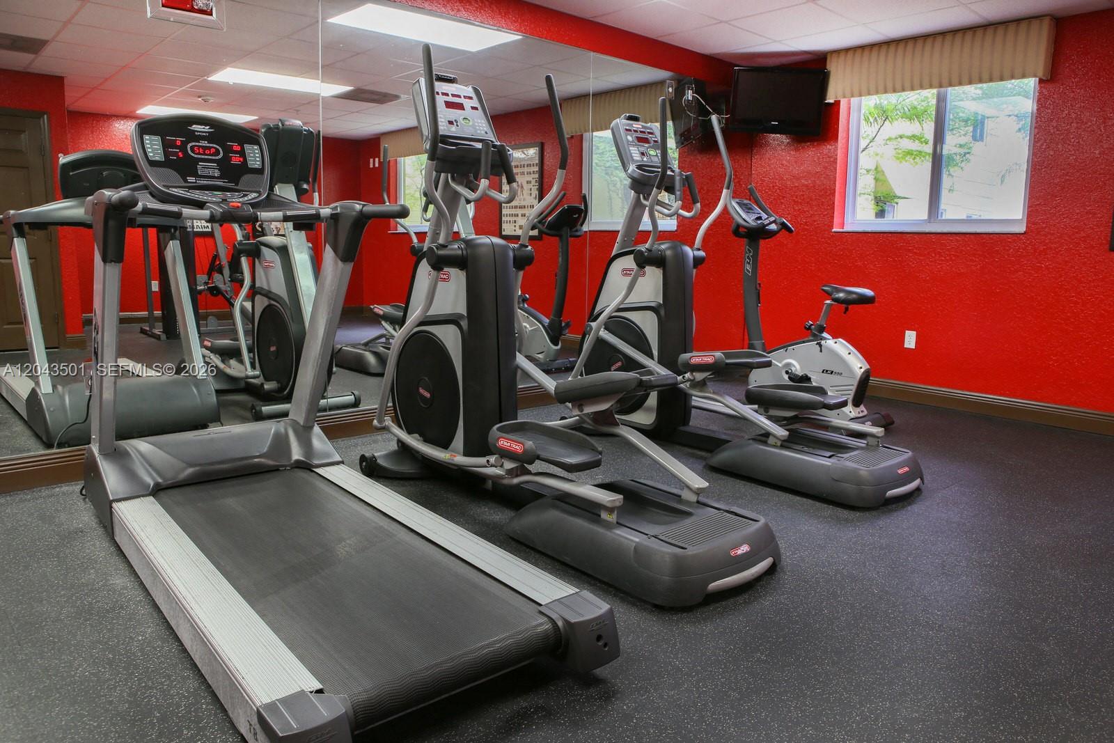 A gym room features a treadmill, two elliptical machines, and a stationary bike on black flooring — 7901 NW 7th Ave # 1102, Miami FL 33150, MIAMI, FL
