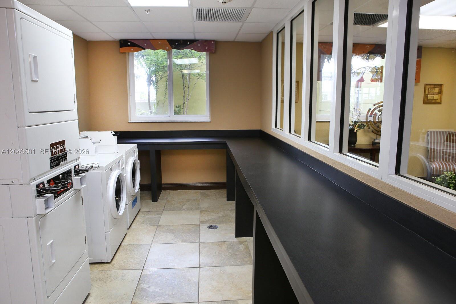 A laundry room features a stacked washer-dryer, two front-load machines, and a long black counter — 7901 NW 7th Ave # 1102, Miami FL 33150, MIAMI, FL
