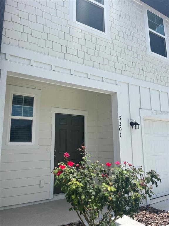 The exterior of a two-story house features white siding, a dark front door, and landscaping — 3301 VESARA DRIVE, DAVENPORT, FL
