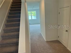A carpeted staircase leads to an upper hallway with a closed door and a window — 3301 VESARA DRIVE, DAVENPORT, FL