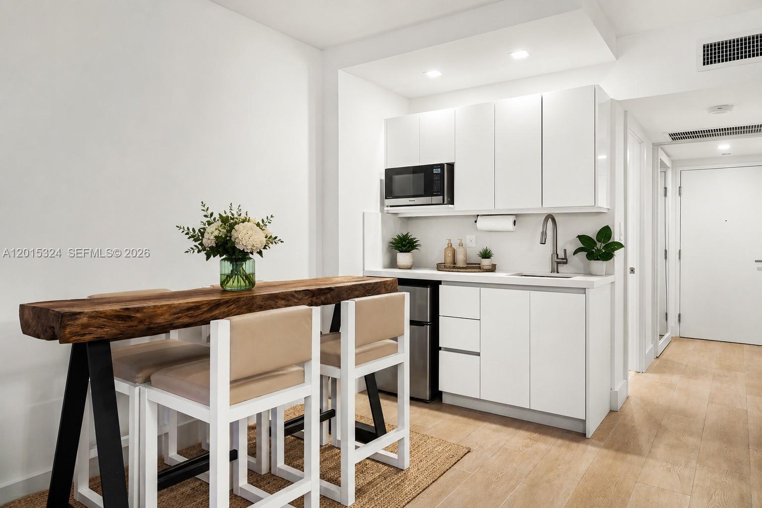 A small kitchen area features white cabinets, a sink, and a wooden breakfast bar — 2301 Collins Ave # 1128, Miami Beach FL 33139, MIAMI BEACH, FL