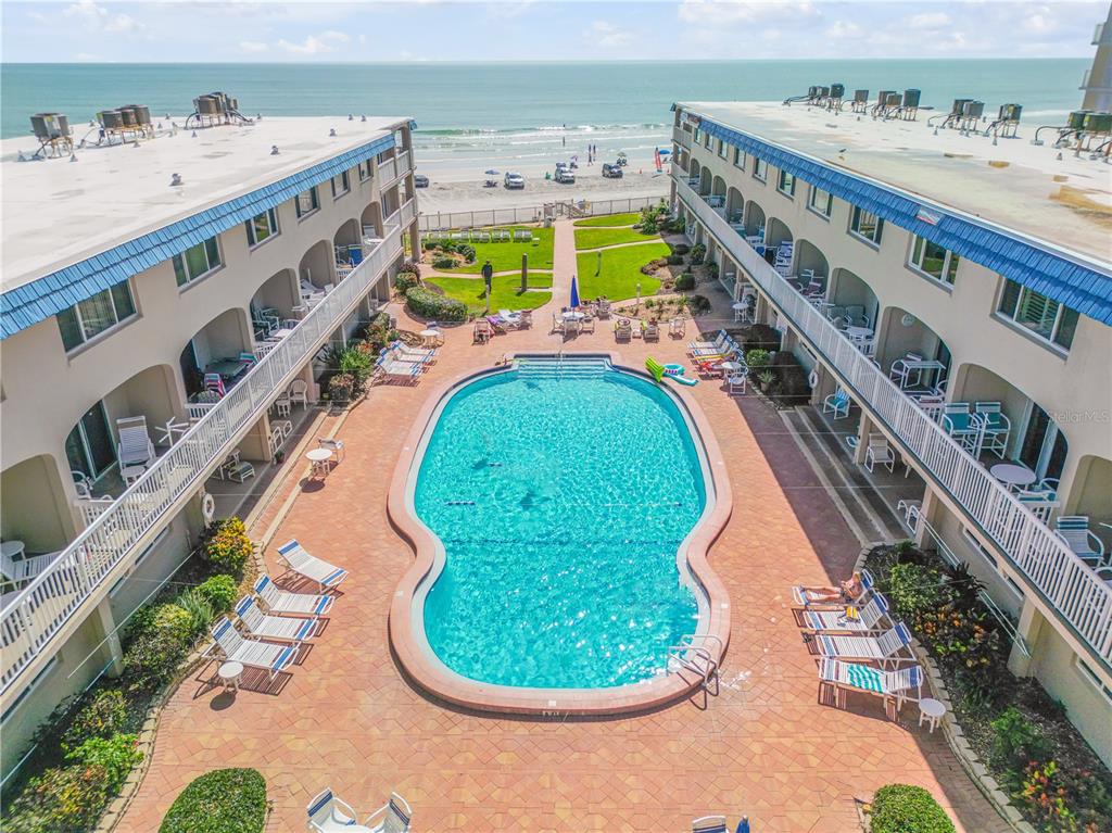 An aerial view of a resort pool courtyard situated between two buildings facing the ocean — 111 N ATLANTIC AVENUE UNIT A105, NEW SMYRNA BEACH, FL