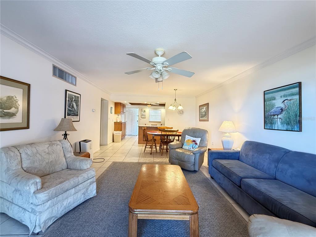 A living room with a blue sofa, patterned armchair, wooden coffee table, and dining area — 111 N ATLANTIC AVENUE UNIT A105, NEW SMYRNA BEACH, FL
