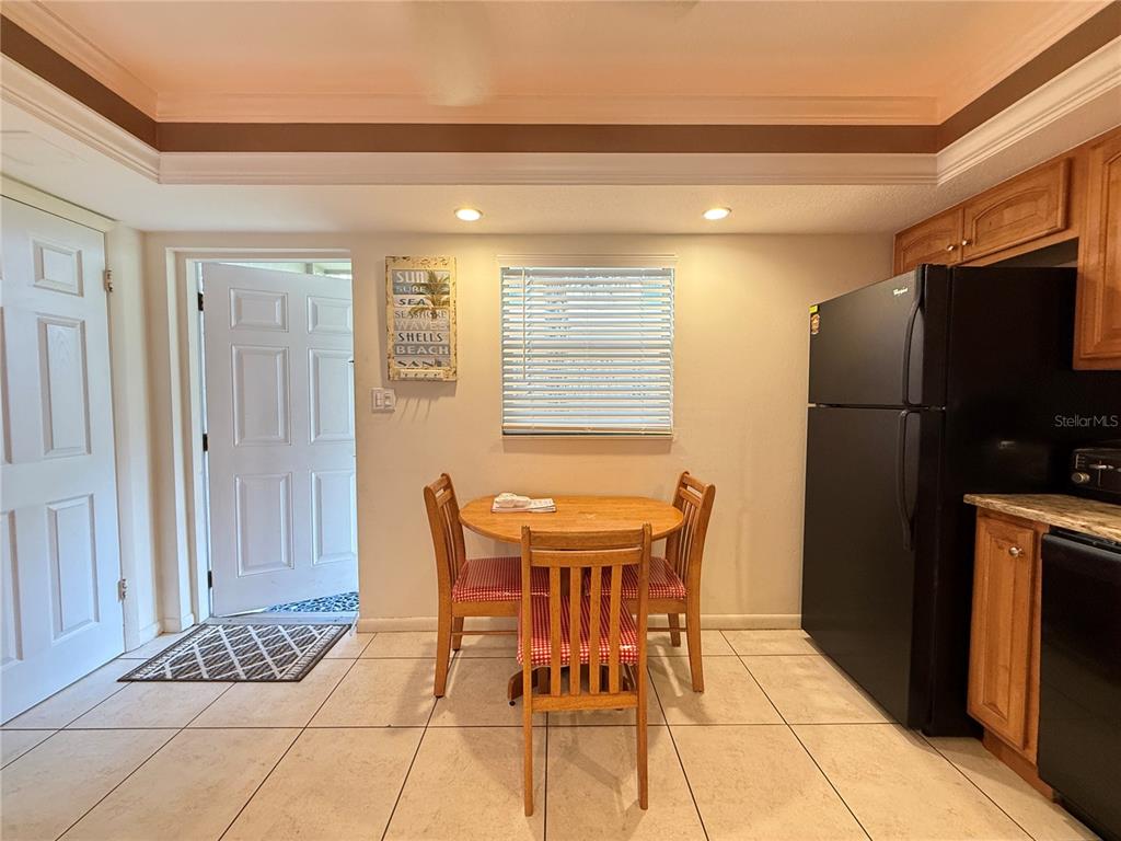 A kitchen dining area features a wooden table, three chairs, tile flooring, and a refrigerator — 111 N ATLANTIC AVENUE UNIT A105, NEW SMYRNA BEACH, FL