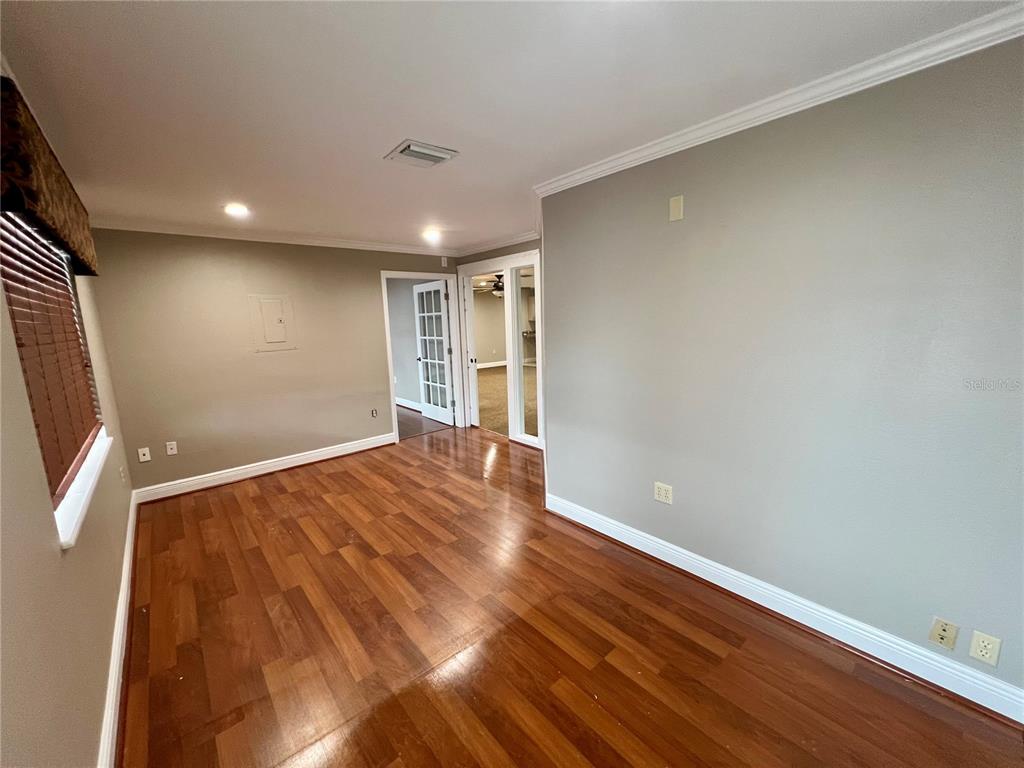 An empty room with wood flooring, light gray walls, and two doorways leading to other rooms — 3360 US HIGHWAY 441/27, FRUITLAND PARK, FL