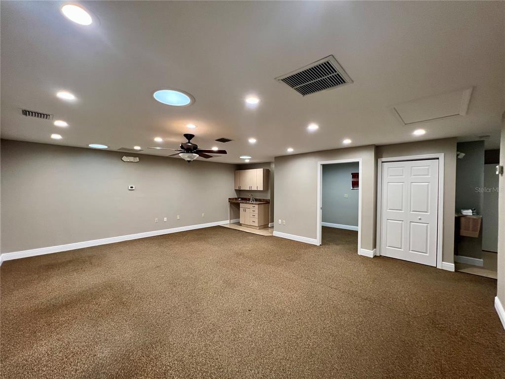 A spacious basement room features brown carpeting, a wet bar, a ceiling fan, and recessed lighting — 3360 US HIGHWAY 441/27, FRUITLAND PARK, FL