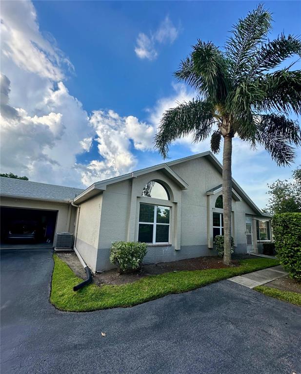 A single-story house with a palm tree, a garage, and a paved driveway — 801 SILVERTHORN LANE, SUN CITY CENTER, FL