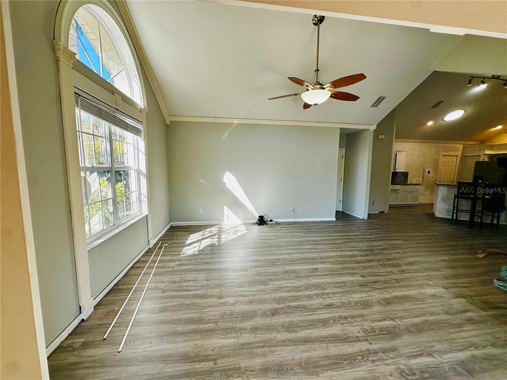 An open-concept living area features light gray walls, wood-look flooring, and a vaulted ceiling — 801 SILVERTHORN LANE, SUN CITY CENTER, FL