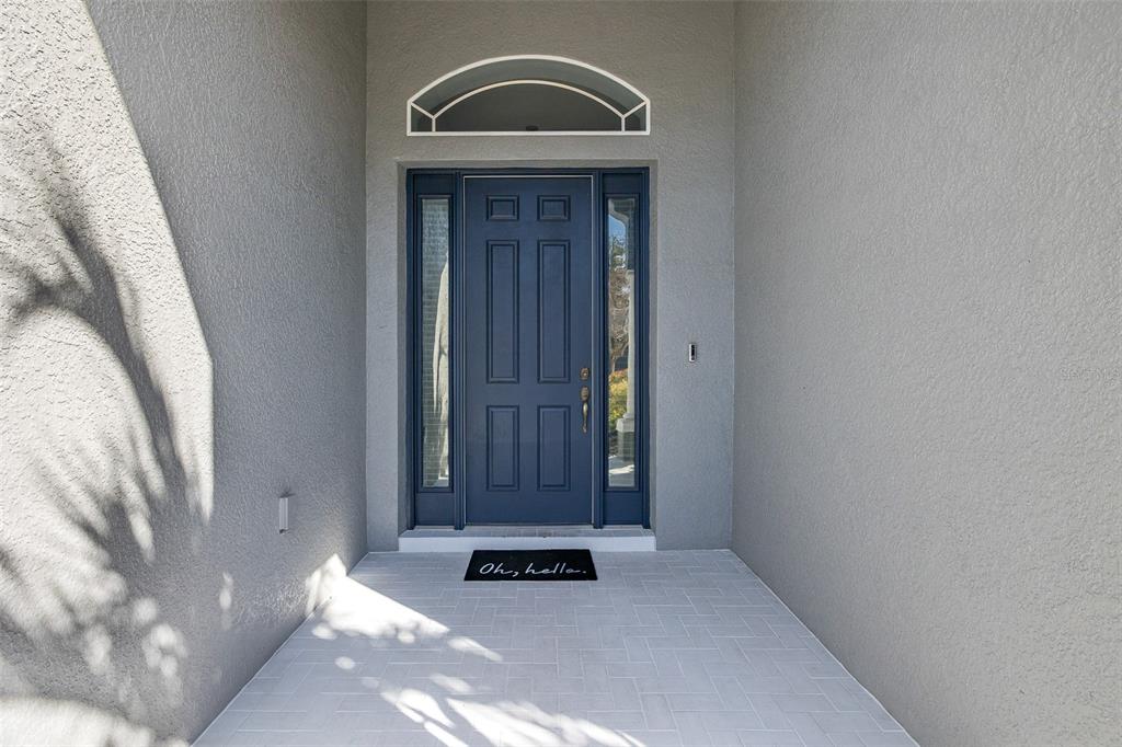 A blue front door with sidelights and an arched transom window sits under a covered entryway — 20301 FALLING ROCK DRIVE, LAND O LAKES, FL