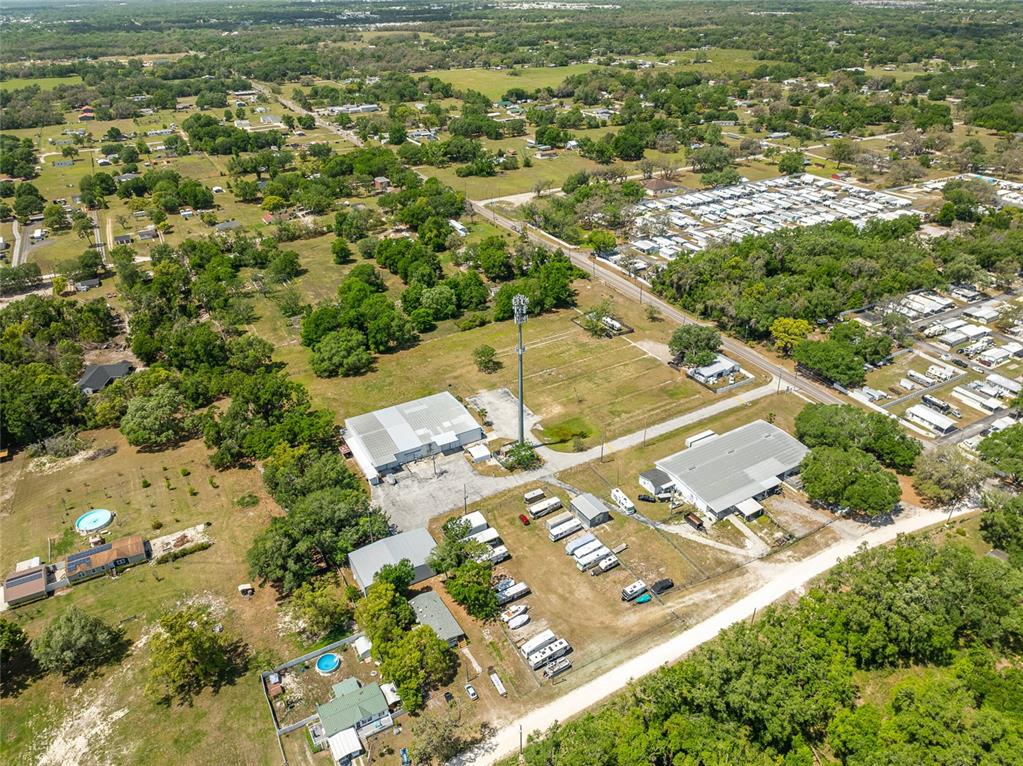 An aerial view shows a rural property with two large warehouses, a cell tower, and trailers — 37150 CHANCEY ROAD, ZEPHYRHILLS, FL