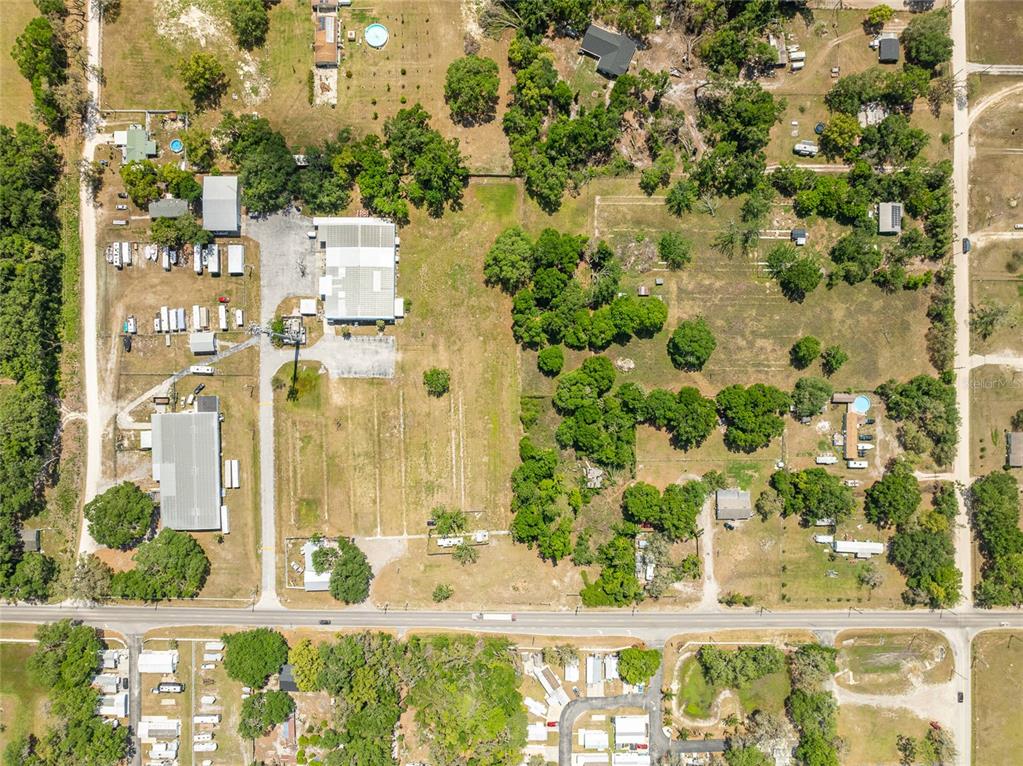 This aerial view shows a large rural property with multiple buildings, trees, and open land — 37150 CHANCEY ROAD, ZEPHYRHILLS, FL