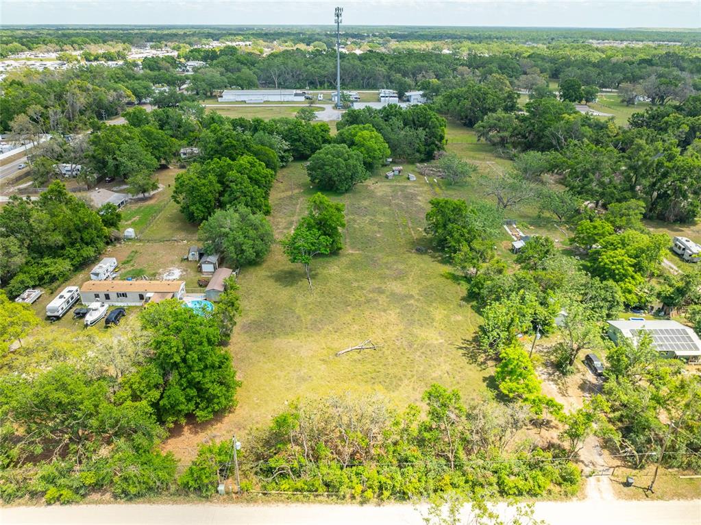 An aerial view shows a large, grassy lot with scattered trees and a mobile home — 37150 CHANCEY ROAD, ZEPHYRHILLS, FL