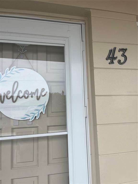 A white storm door with a welcome sign and the number 43 on the exterior wall — 2295 BELGIAN LANE UNIT 43, CLEARWATER, FL