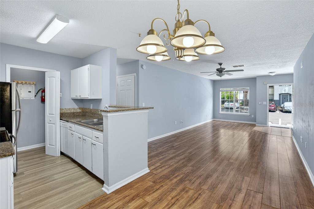 A kitchen with white cabinets and granite countertops opens into a living area with flooring — 4320 S KIRKMAN ROAD UNIT 1511, ORLANDO, FL