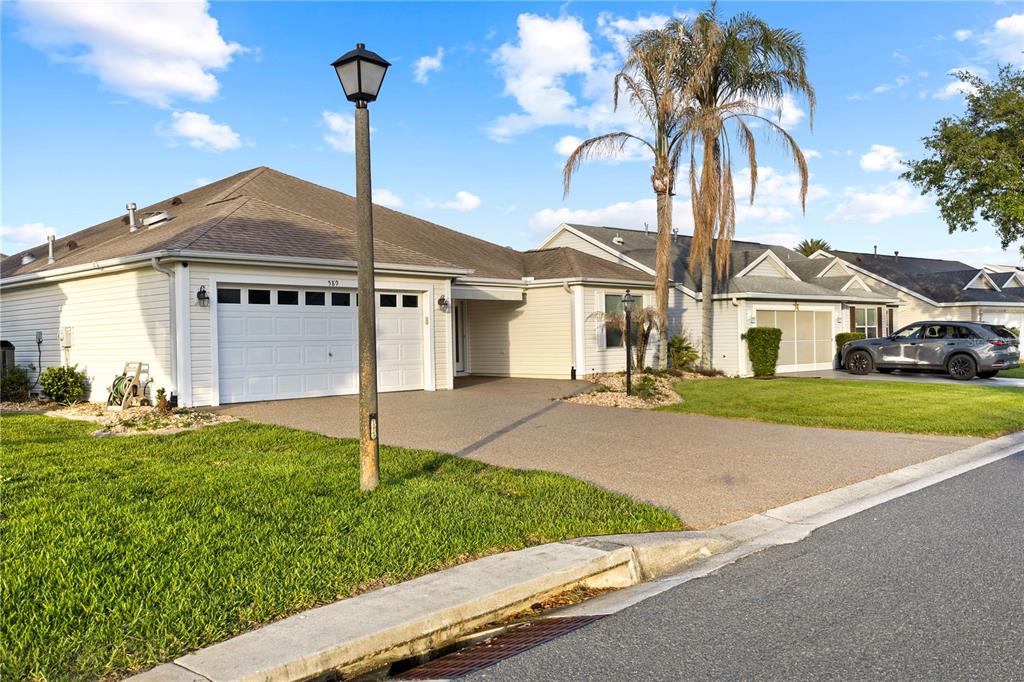 A single-story house with a white garage and a driveway under a blue sky — 589 SHERWOOD STREET, THE VILLAGES, FL